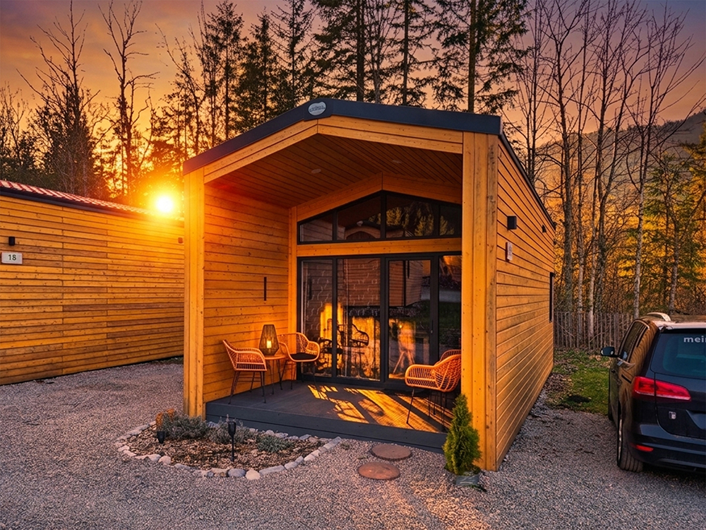 Das Alpenchalet Wendelstein in stimmungsvoller Abendsonne von außen mit Blick auf die gemütlich eingerichtete Terrasse und privatem Stellplatz direkt am Chalet für gemütliche und laue Nächte.